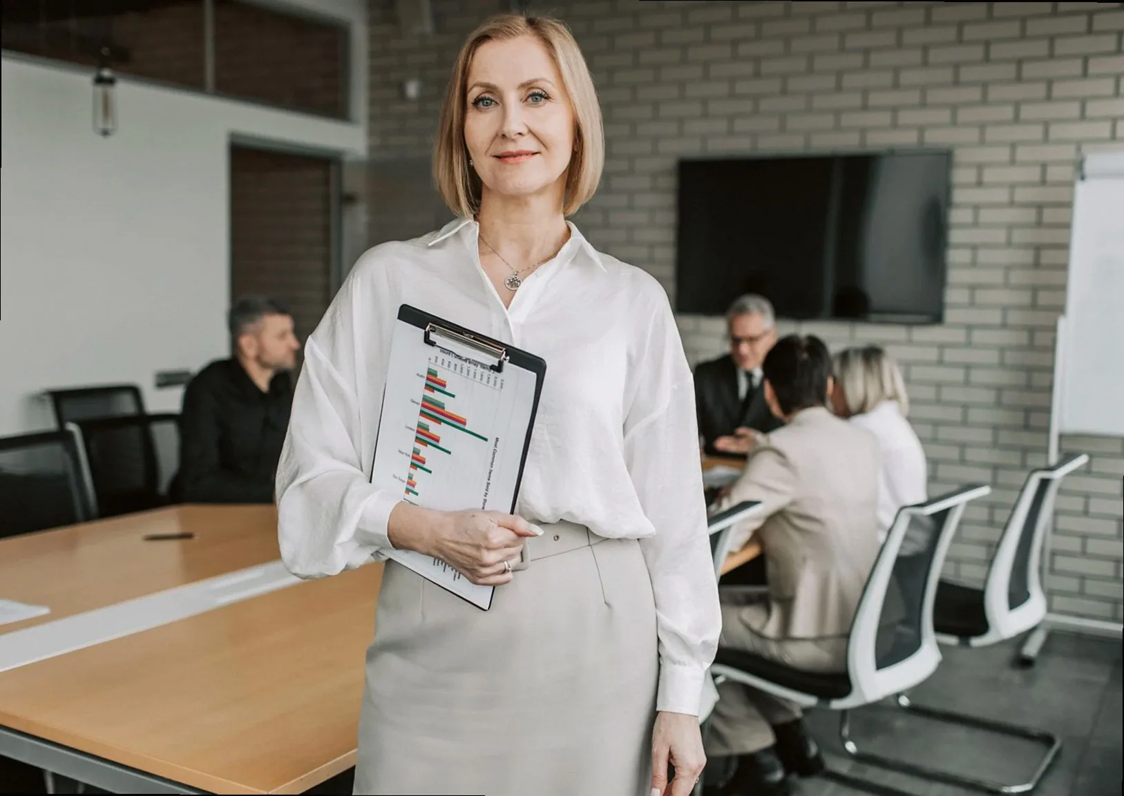 Professional businesswoman holding a clipboard during an office meeting, showcasing leadership in a corporate environmen